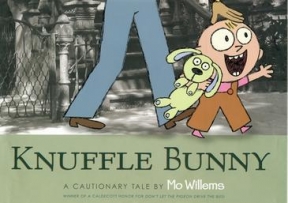 Knuffle Bunny book cover featuring a small child walking along a street holding a bunny next to the legs of an adult. 