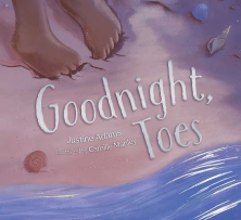 The cover shows the water’s edge at the beach with a child’s toes buried in the sand. The title “Goodnight, Toes” is written in white in the sand.