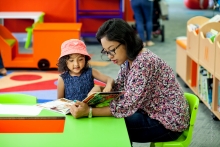 Mother and toddler daughter reads a picture book in The Story Place